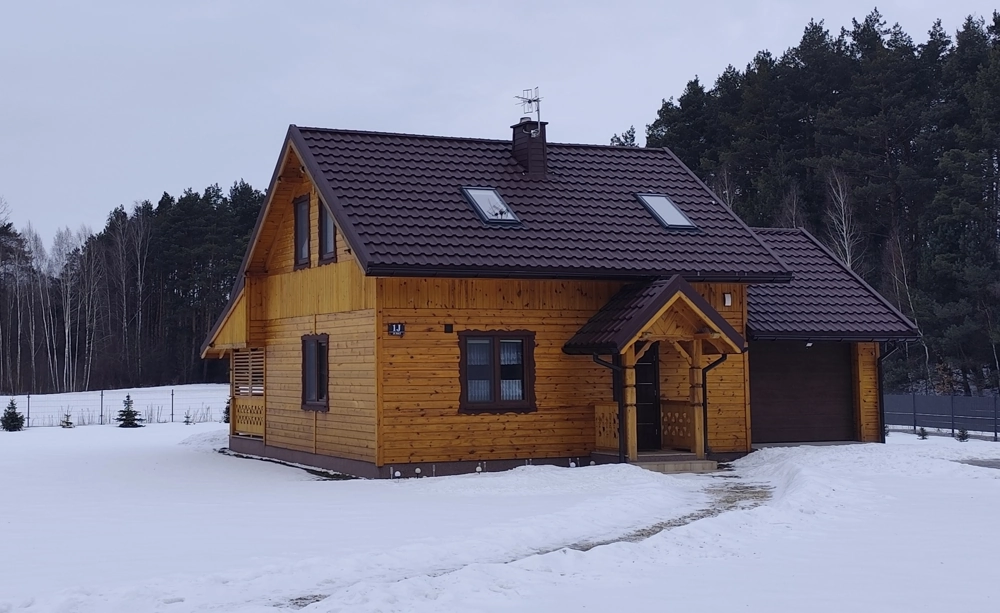 Domy z bali na zimowej działce z widocznym podjazdem i garażem